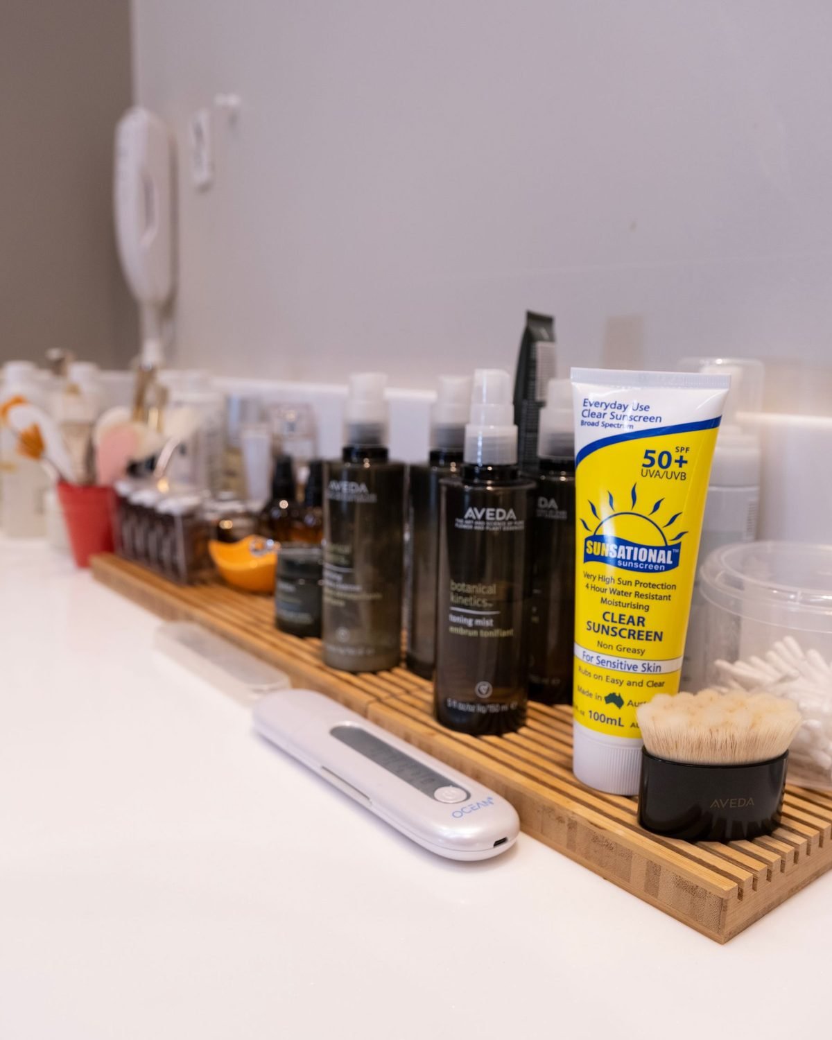 bathroom shelf with skincare products and a tube of toothpaste on a wooden tray