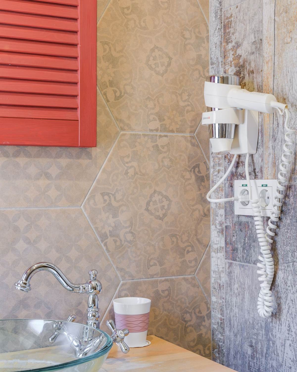bathroom sink area with a wall-mounted hair dryer and a round mirror