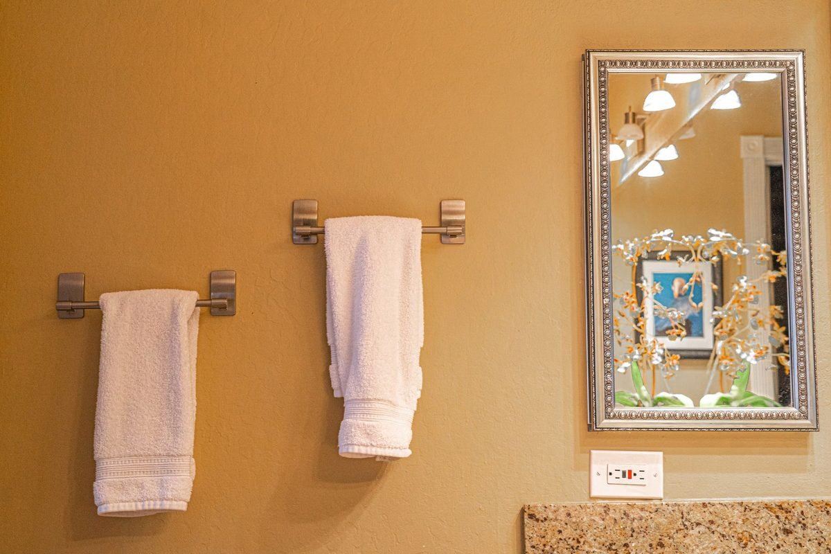 bathroom wall with towel bars, hanging towels and a framed mirror