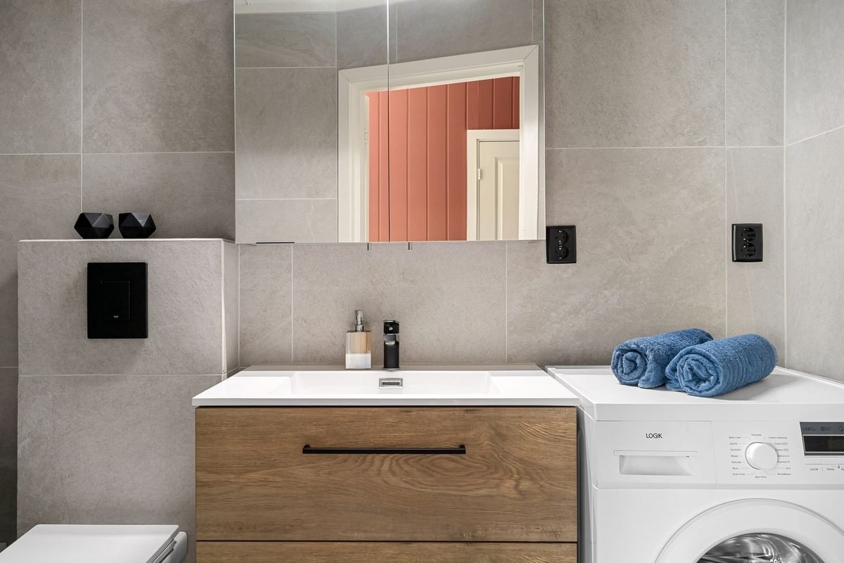 bathroom with a wooden vanity, a mirror and a washing machine