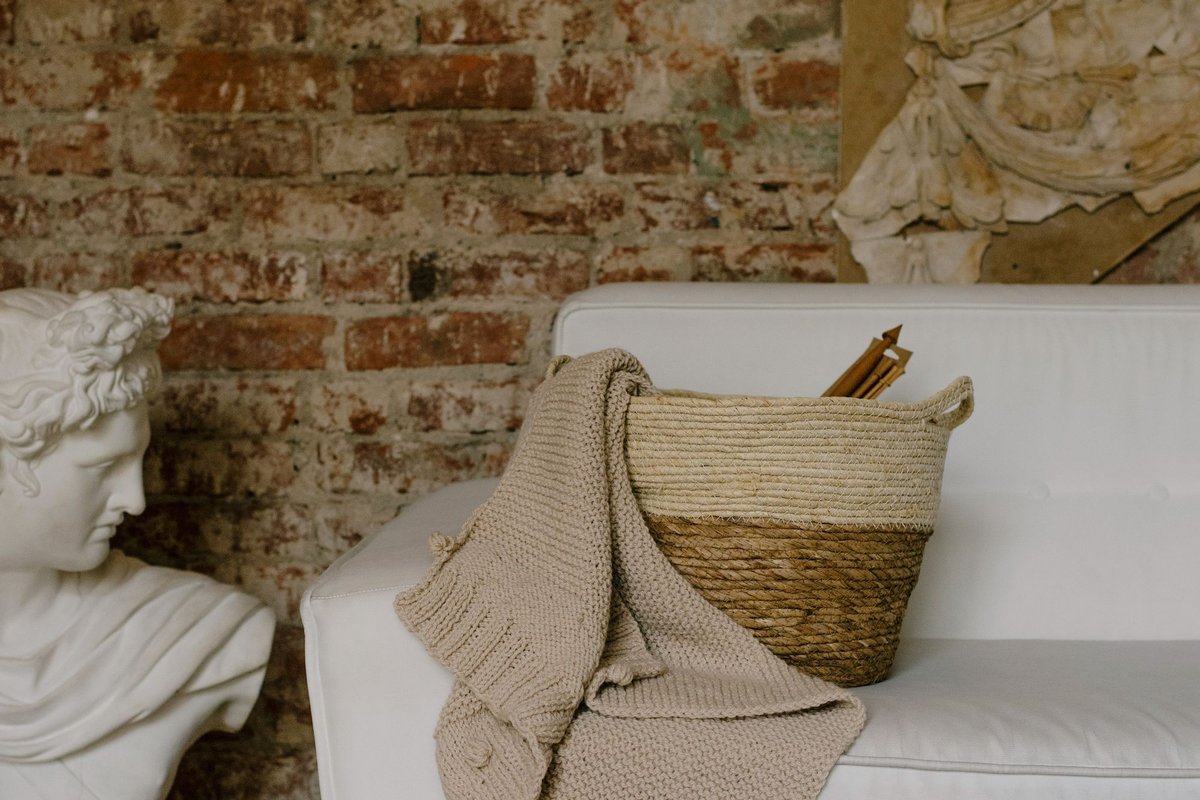 Wicker basket with a knit blanket beside a sofa