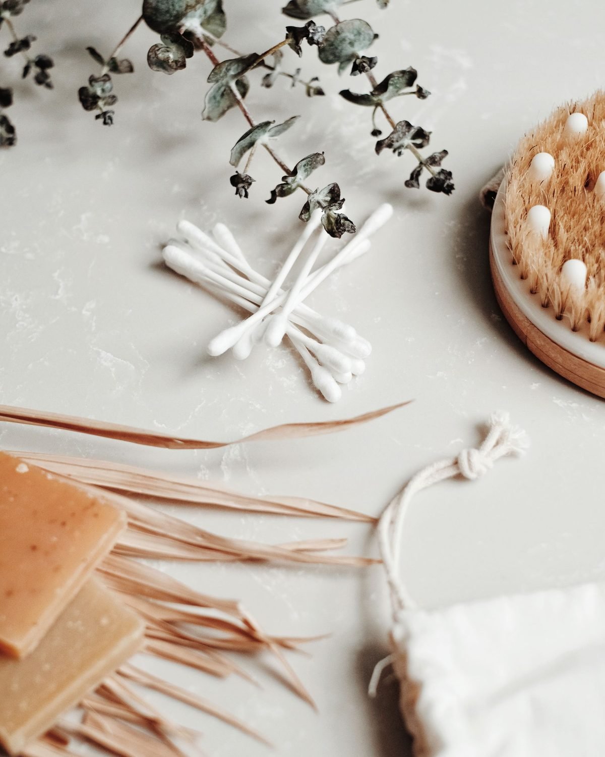 cotton swabs, wooden brush and small bath accessories on a white surface