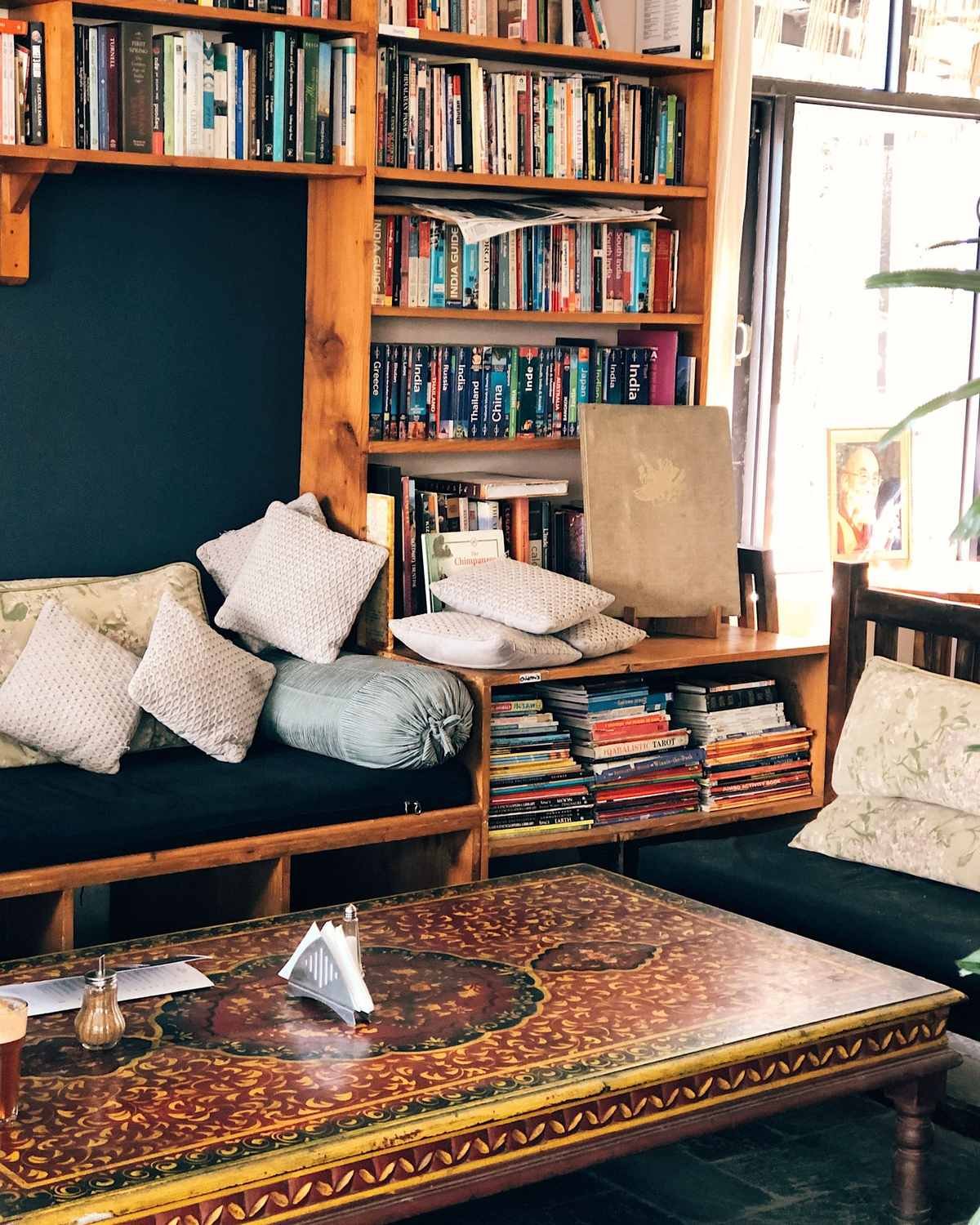cozy reading corner with a wooden bookshelf, couch cushions and a coffee table