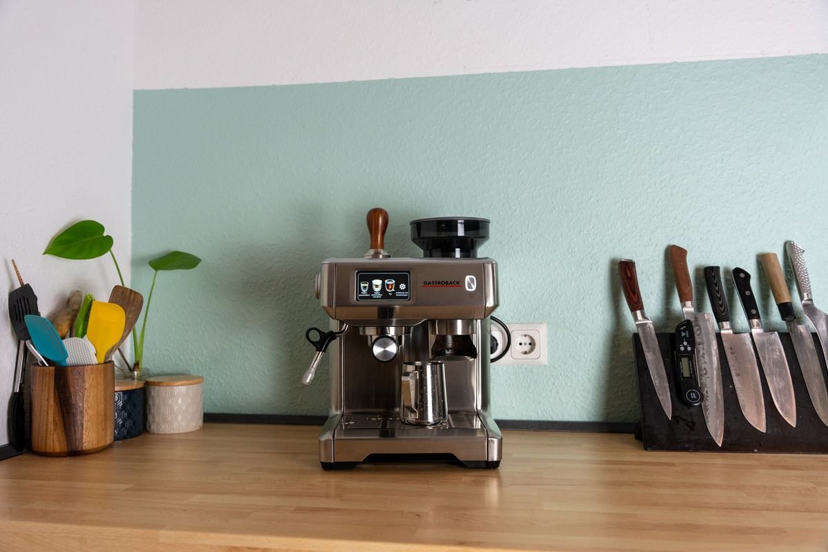 espresso machine and knife block on a wooden kitchen counter by a mint wall