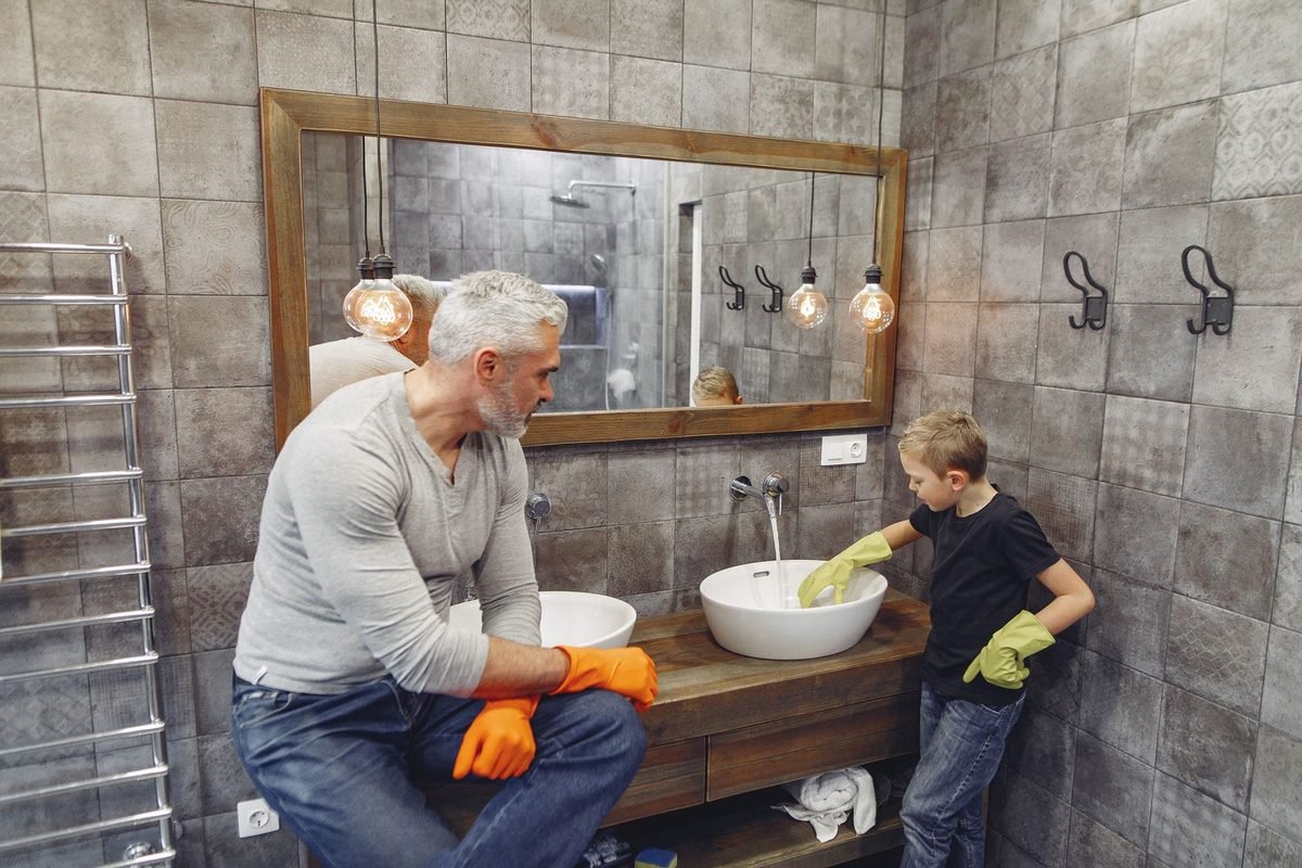 father and young child cleaning a bathroom sink together