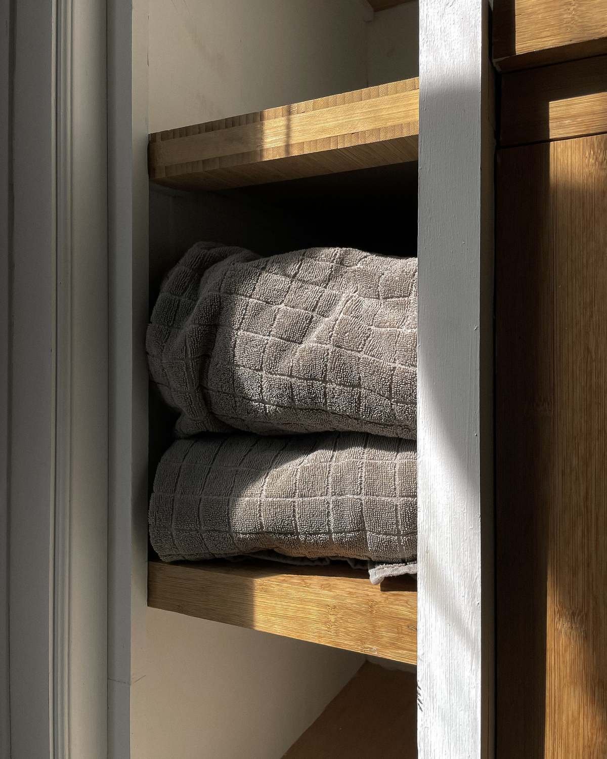 folded gray towels stacked on a shelf inside a cabinet