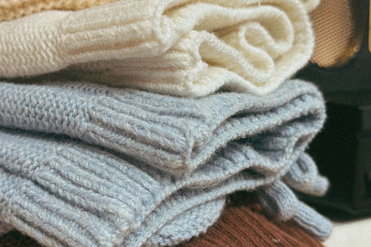 Stack of folded knitted sweaters ready for a closet organizer
