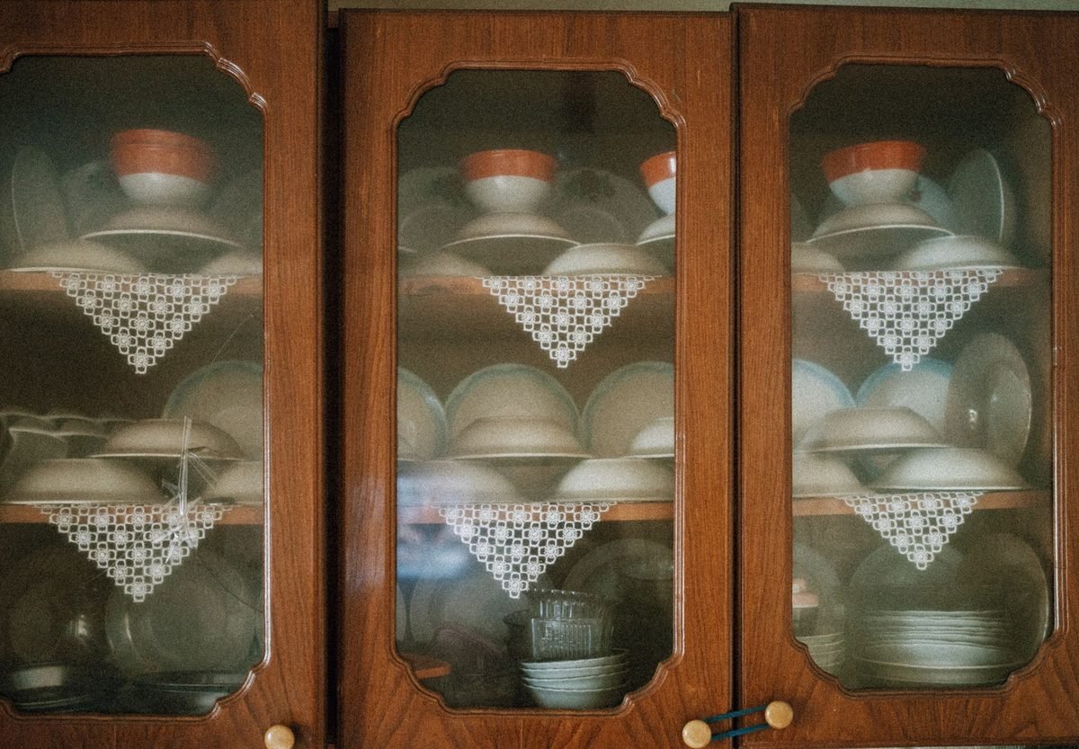 glass-front wooden kitchen cabinets holding stacked plates and bowls