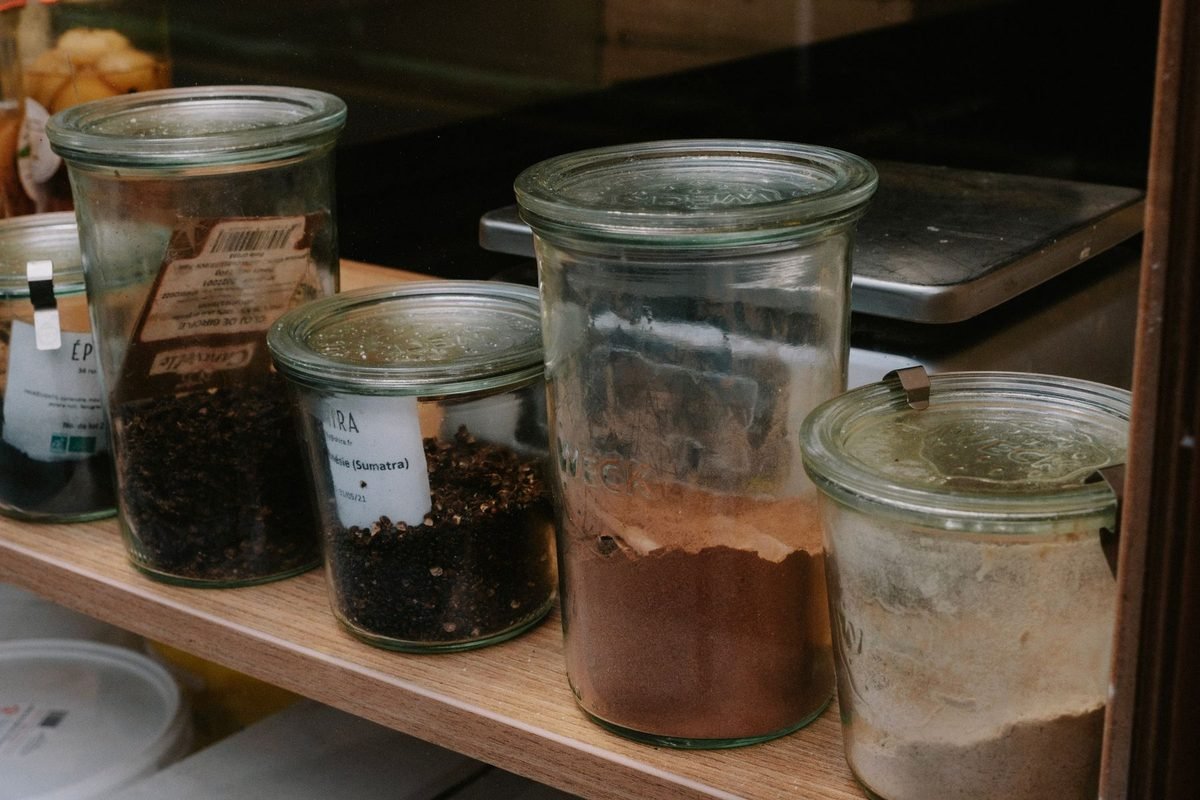 glass jars of spices and dry goods on a wooden shelf