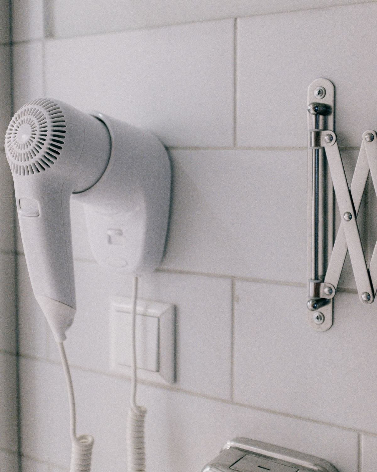 hair dryer mounted on a white tiled bathroom wall