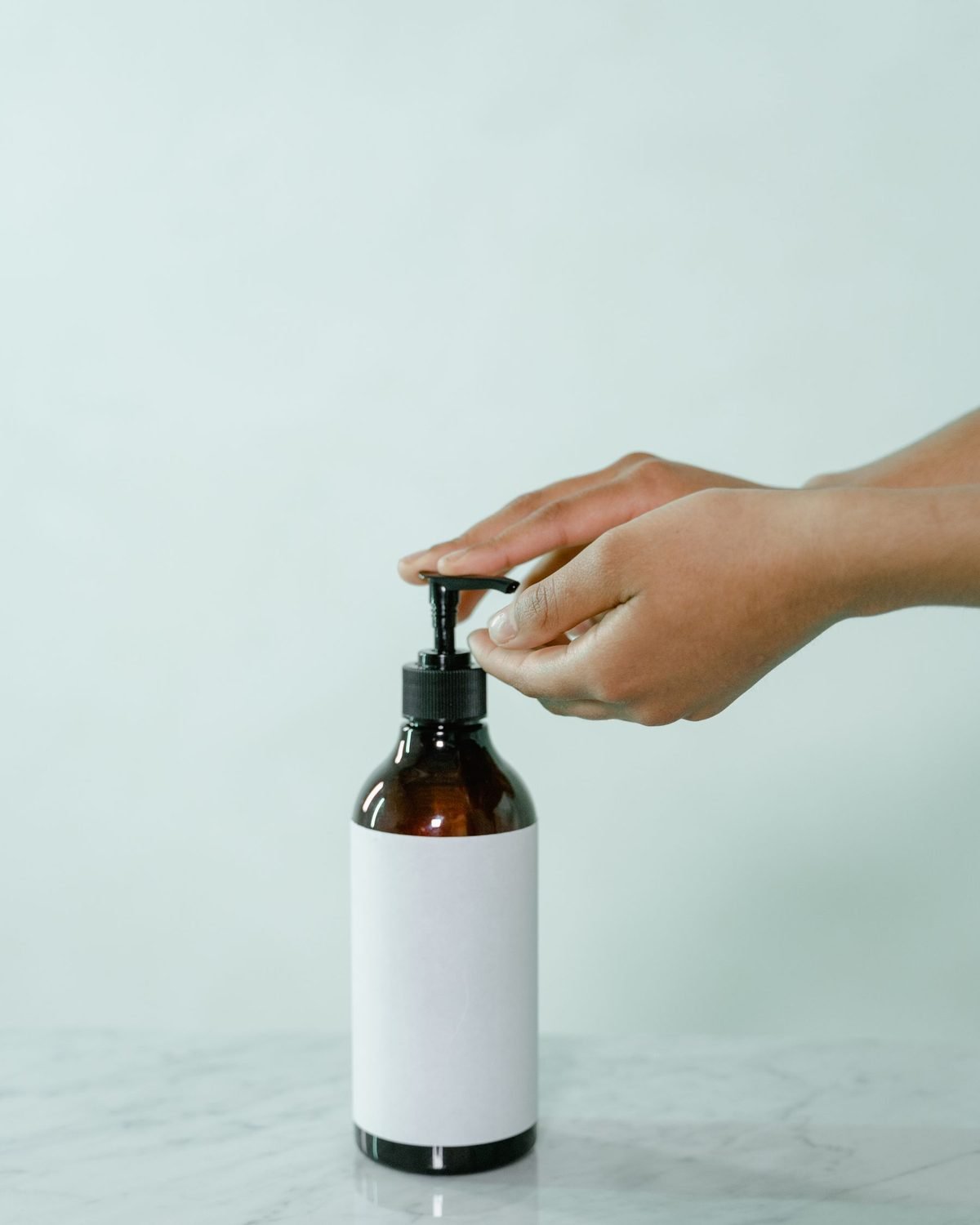hand pressing the pump of a plain white soap bottle