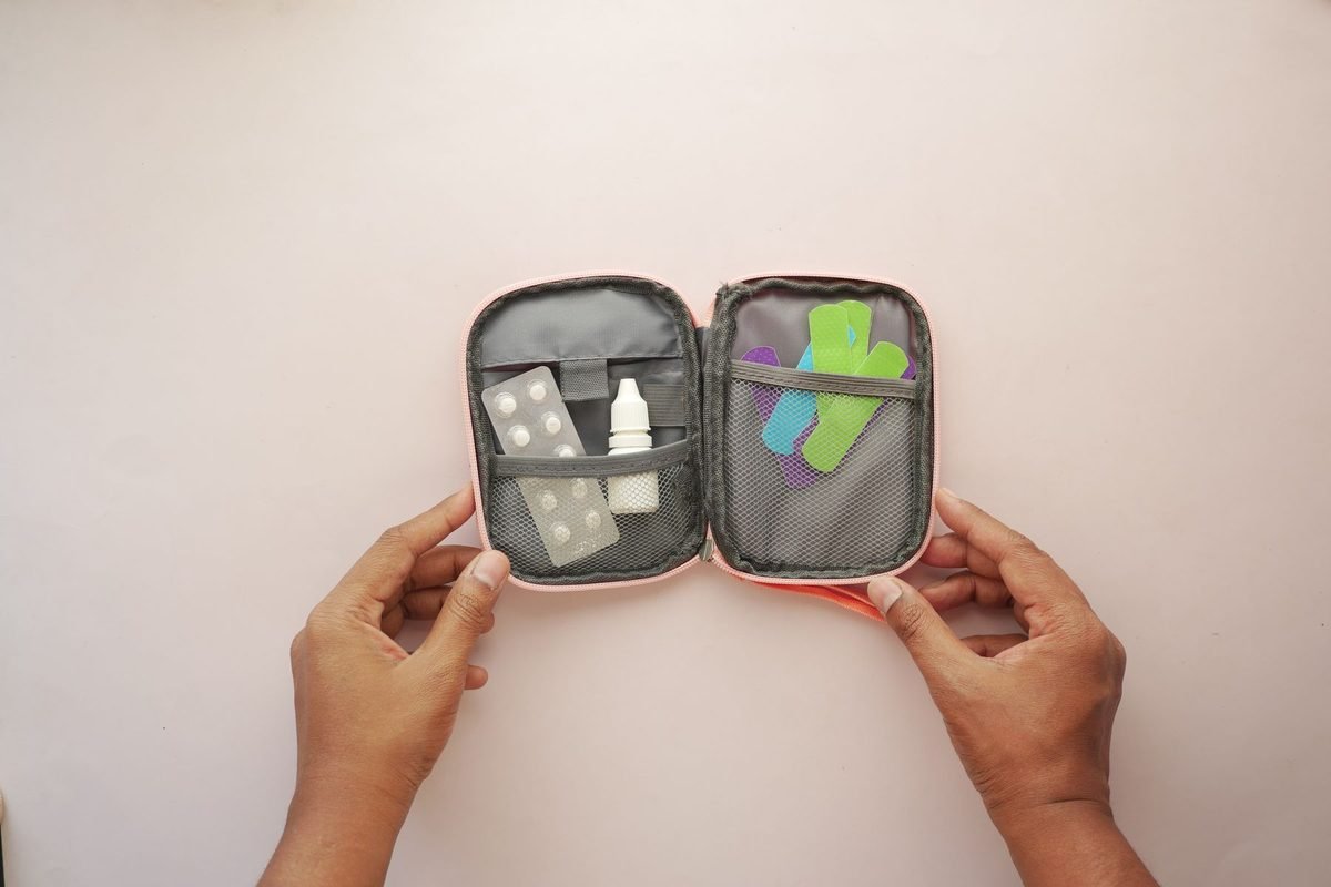 hands holding an open zip pouch with first aid supplies