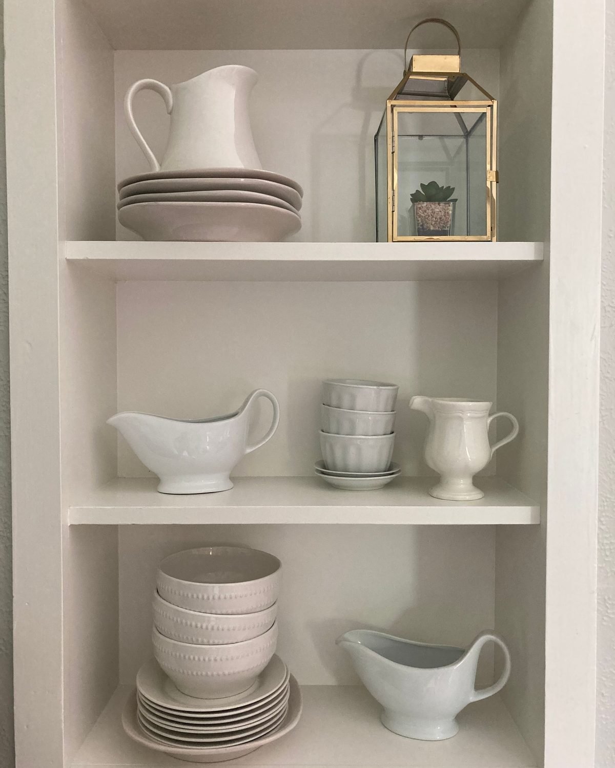 white dishes and ceramics neatly arranged on kitchen shelves