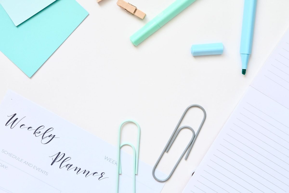 weekly planner, pens and paper clips laid out for a january organization challenge