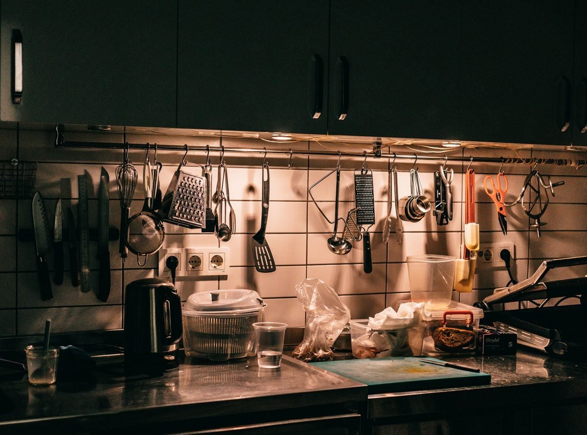 kitchen backsplash with utensils, ladles and tools hanging from a long rail