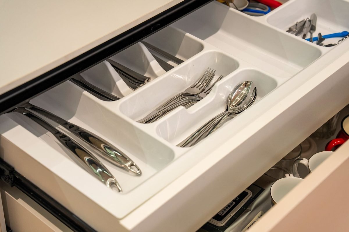 kitchen drawer with a white cutlery organizer holding forks, spoons and knives