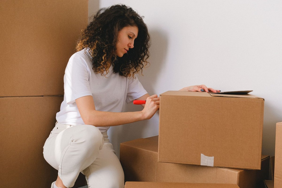 woman labeling storage boxes while organizing a small apartment