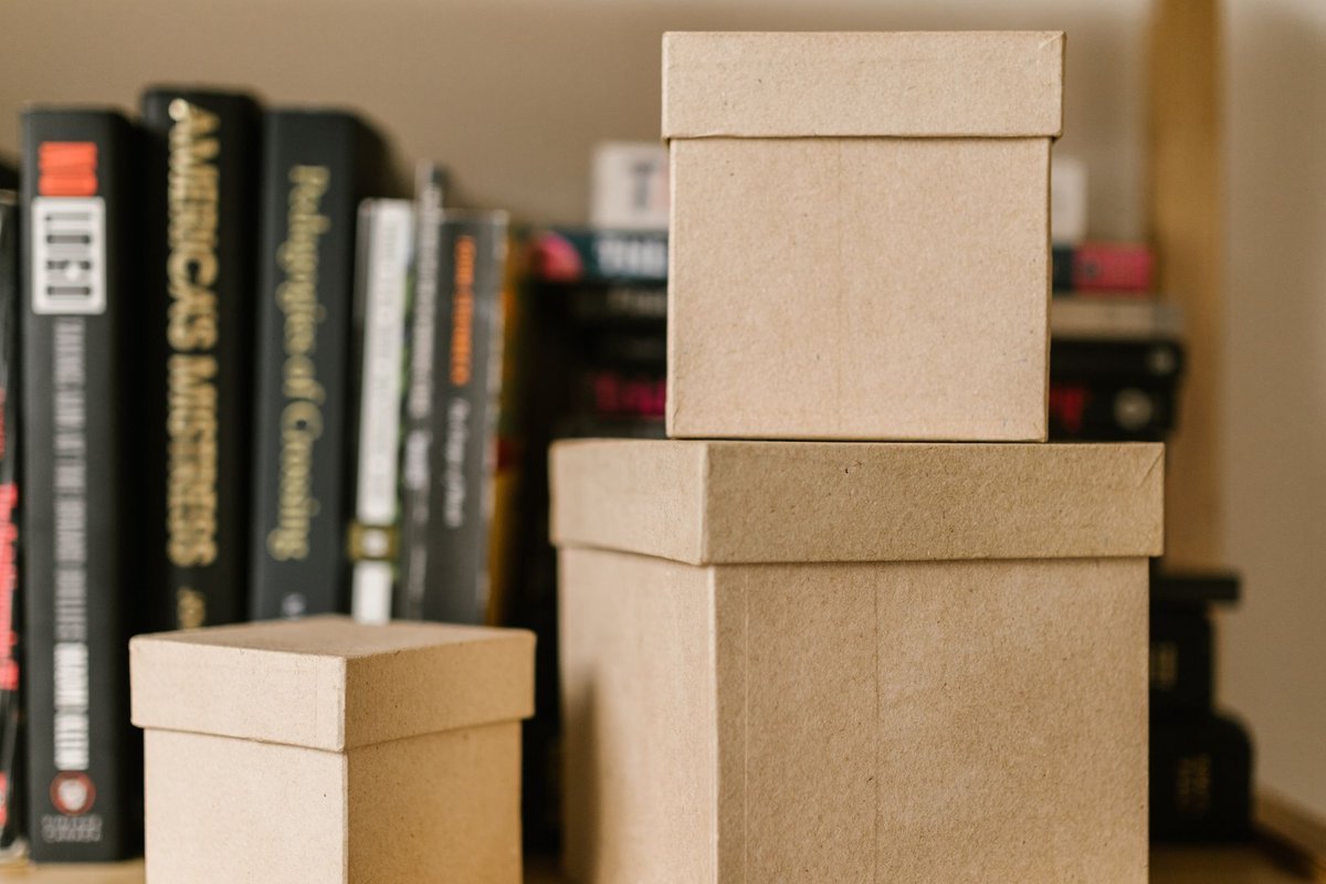Brown storage boxes on a wooden shelf between books