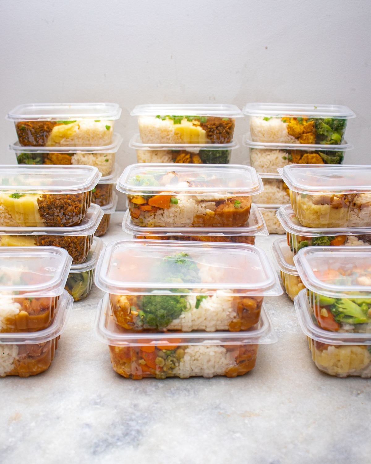 meal prep containers filled with rice and vegetables stacked together
