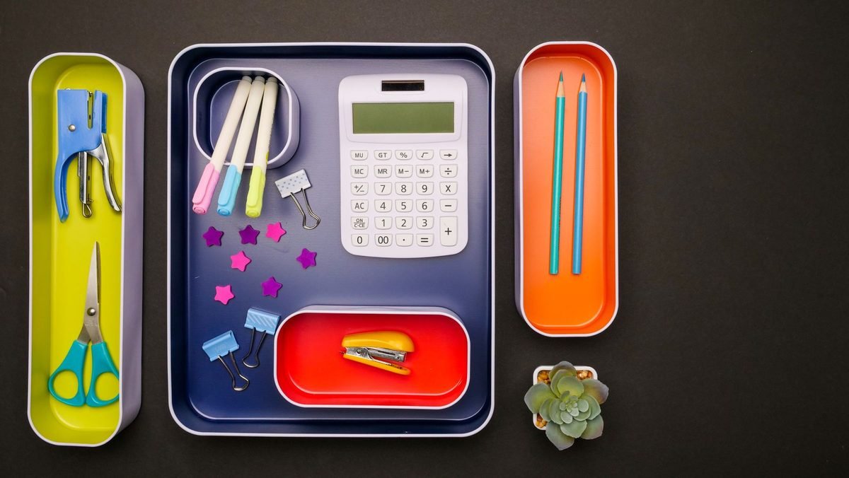 organized desk accessories in colorful trays including a calculator and pens