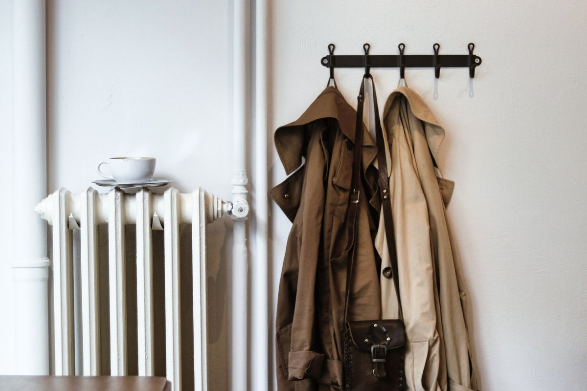 Coats and a tote bag hanging on hooks in a small entryway
