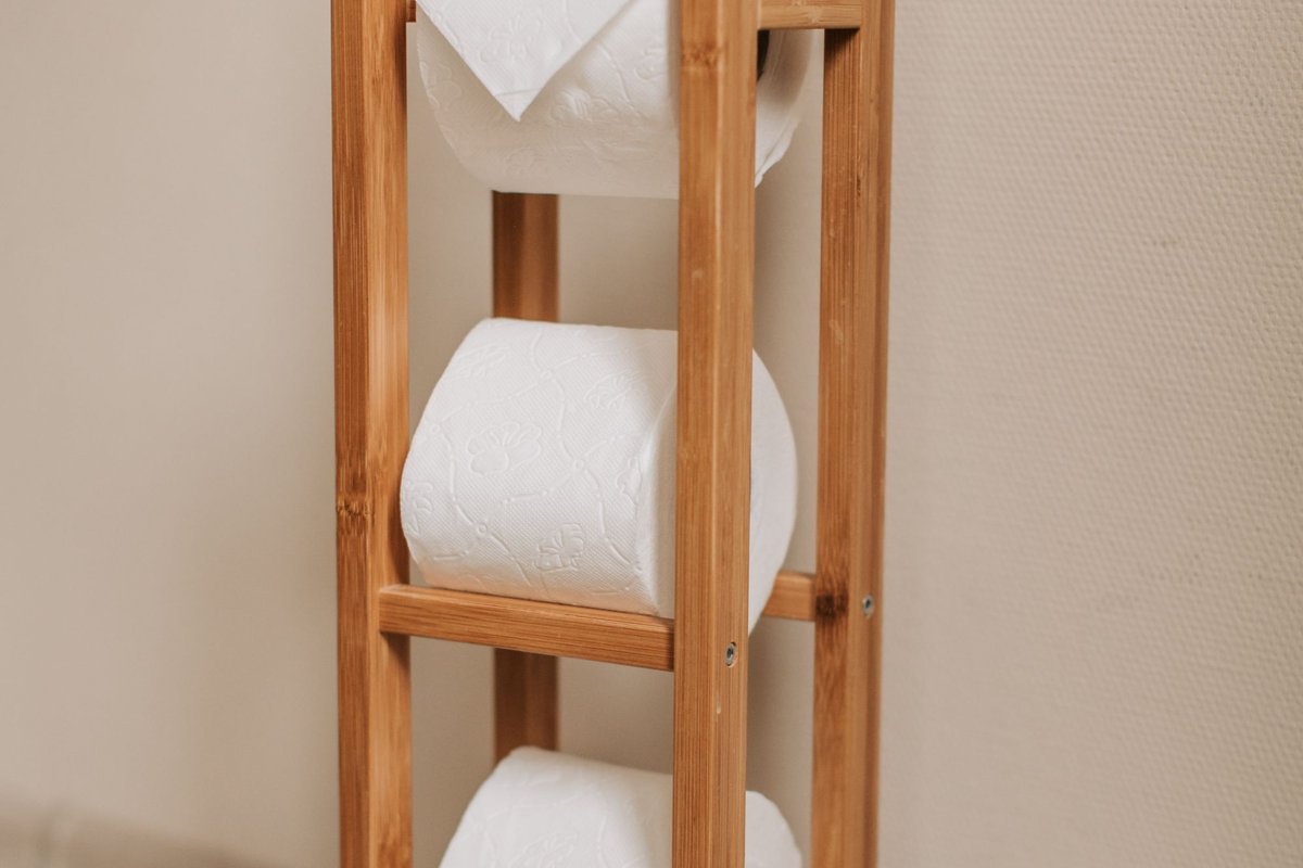 Toilet paper rolls stored on a wooden bathroom rack