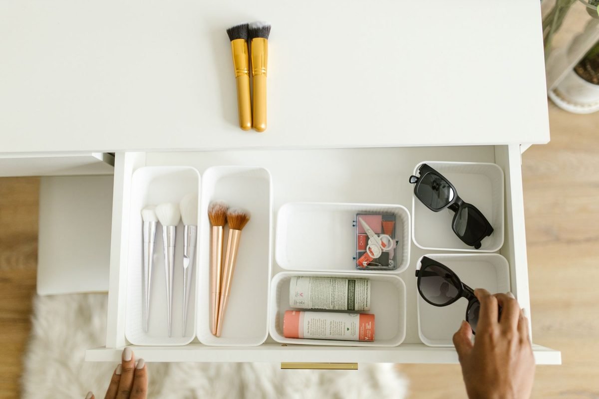 person organizing a drawer with small white trays