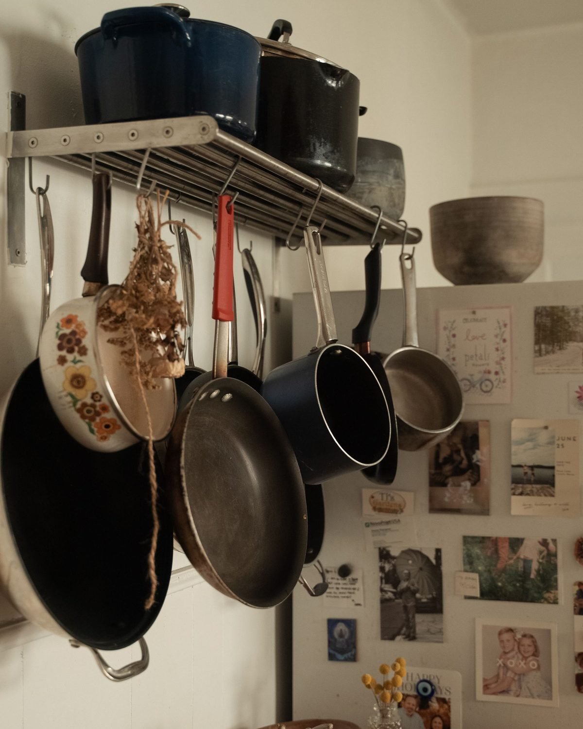 pots and pans hanging from a rack above a small kitchen counter