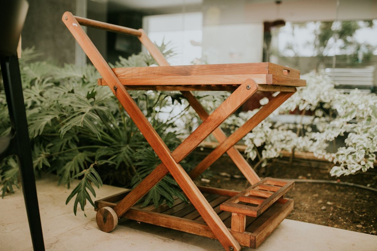 Wooden rolling cart used as extra storage beside plants