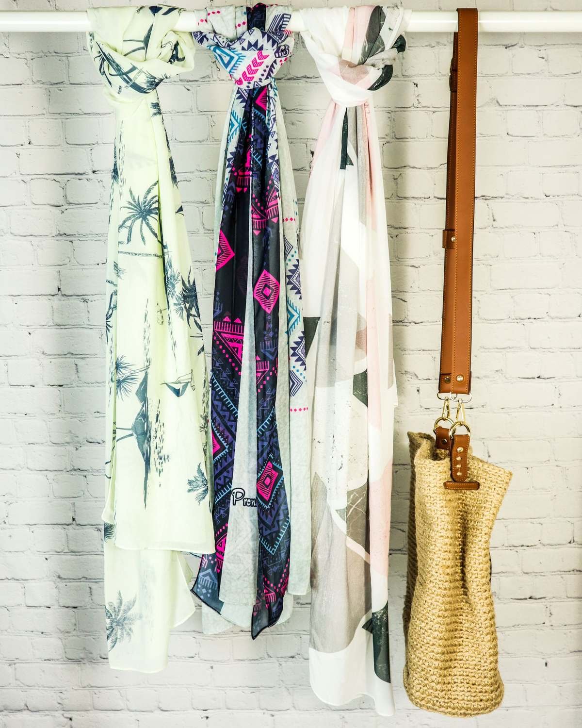 scarves and a shoulder bag hanging from a rod