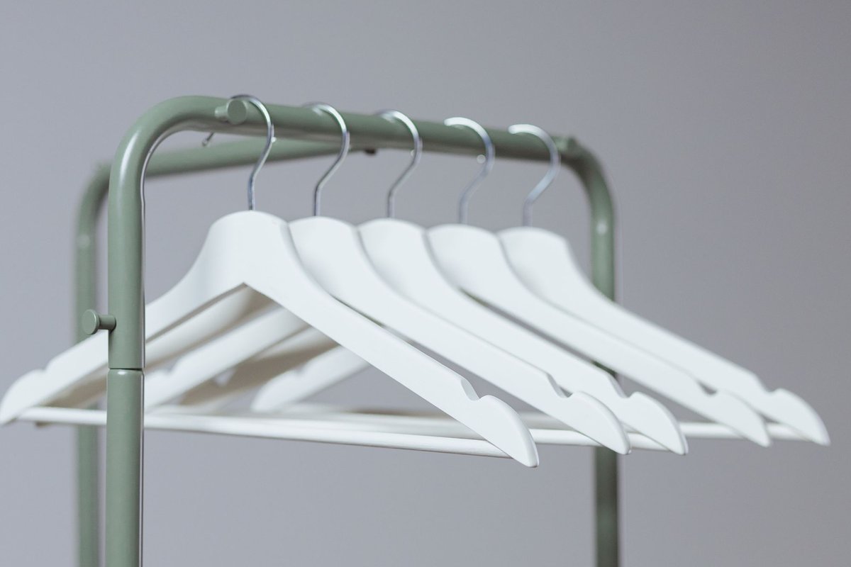 Matching slim white hangers on a clothes rack