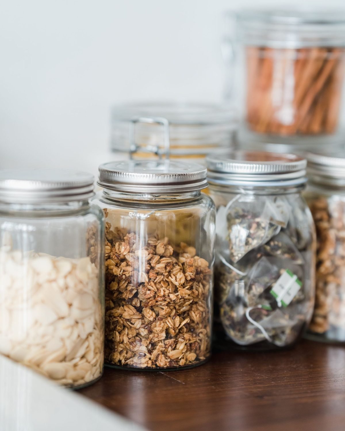 snacks and chips stored in clear glass jars on a kitchen counter