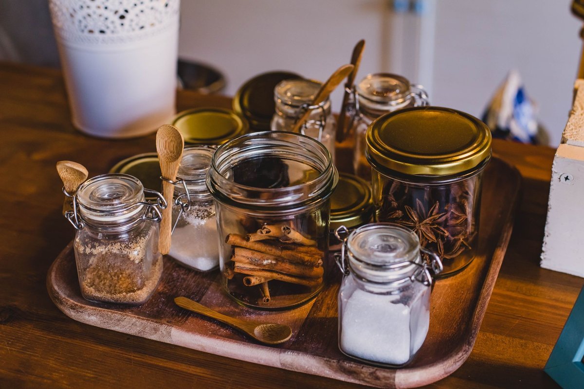 Glass spice jars grouped on a tray for easy reach in a kitchen corner