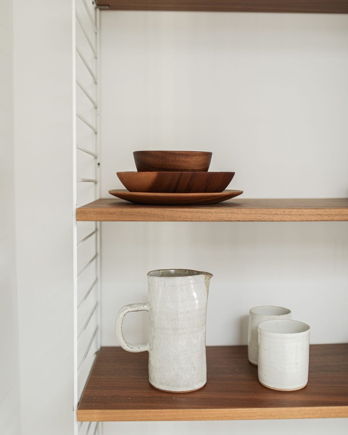 stacked dinnerware and jugs arranged on wooden shelves