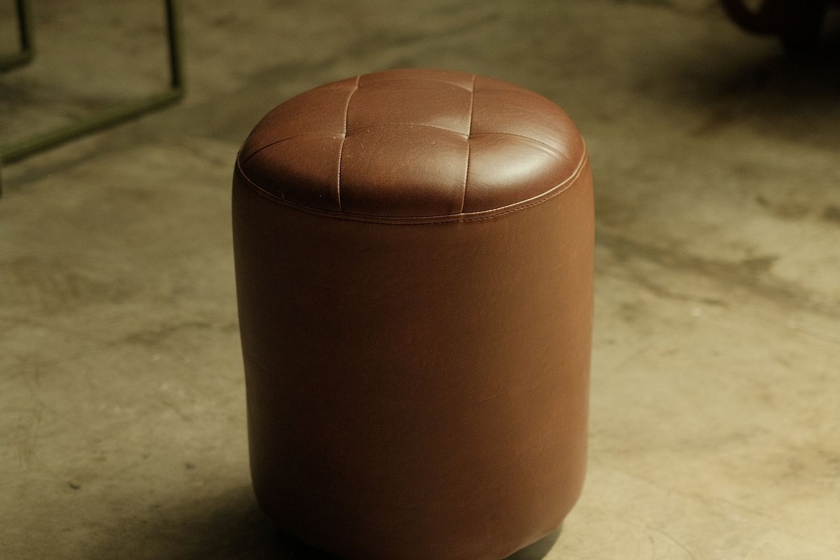 Brown leather pouf ottoman in a small living room