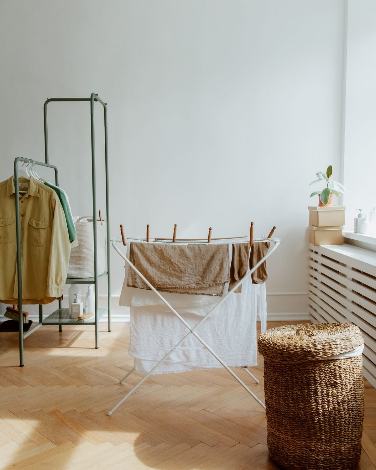 tidy small laundry room with clothes drying and a wicker basket