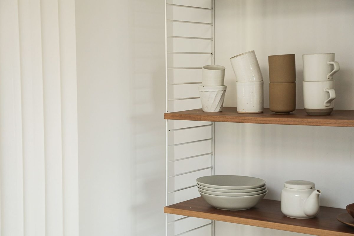 white mugs, bowls and plates on open wooden kitchen shelves