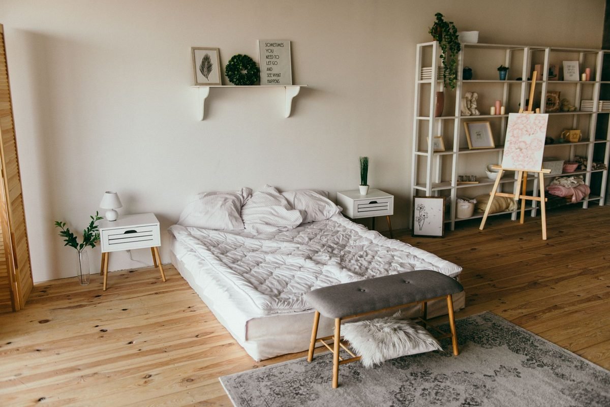 white wooden shelf beside a neatly made bed in a calm bedroom