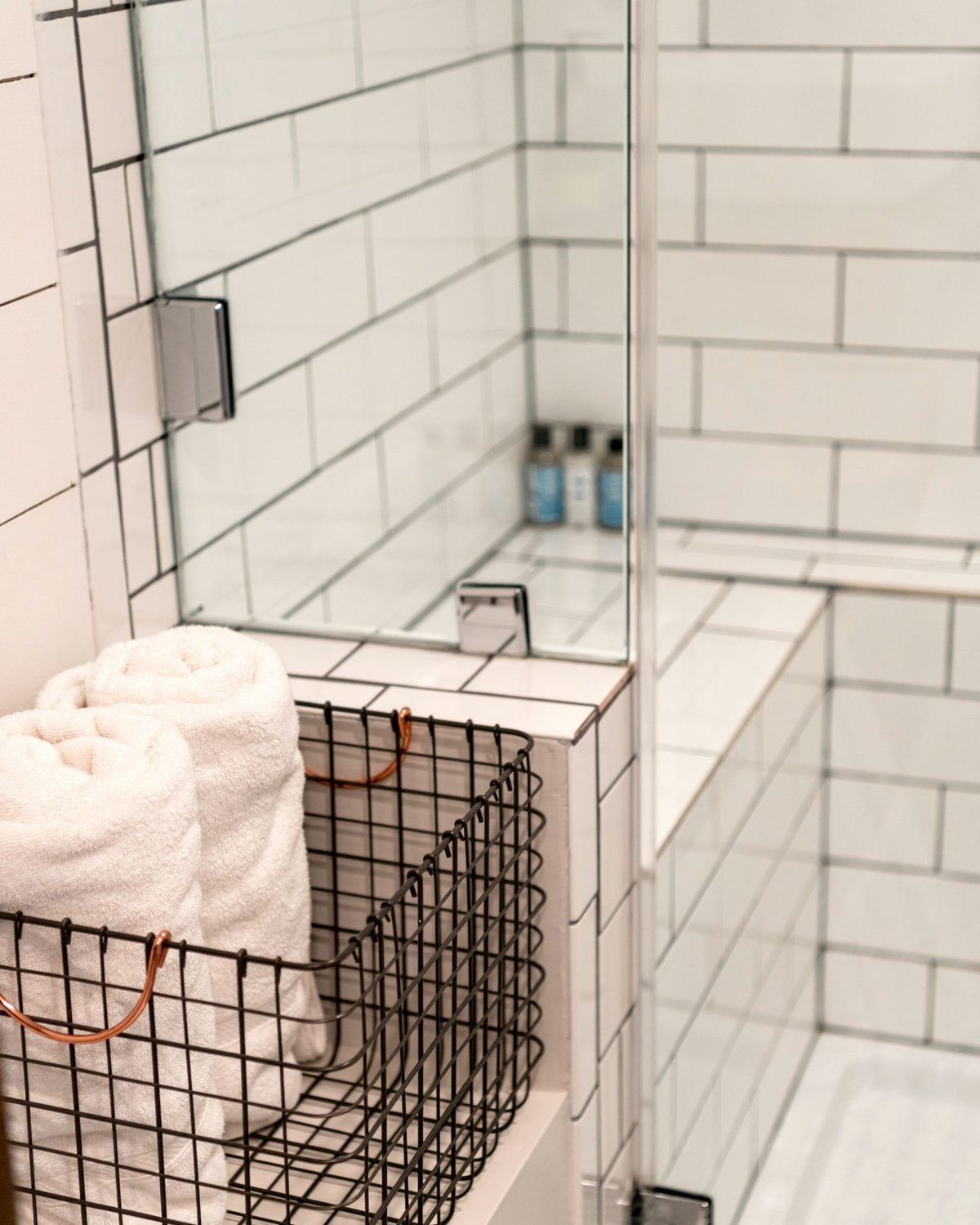 wire basket holding a towel beside a tiled bathroom wall