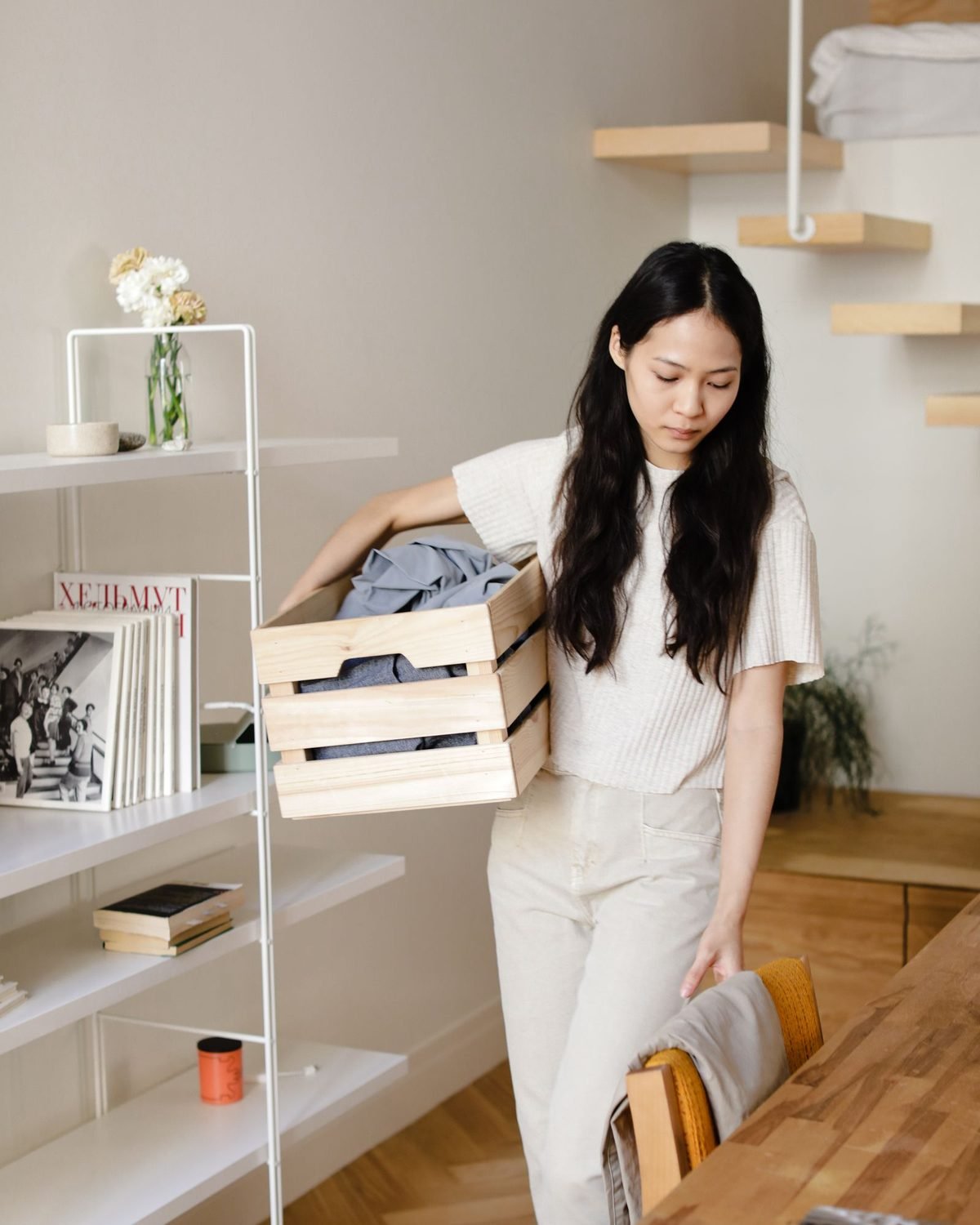 woman collecting laundry from a basket in a bright modern home