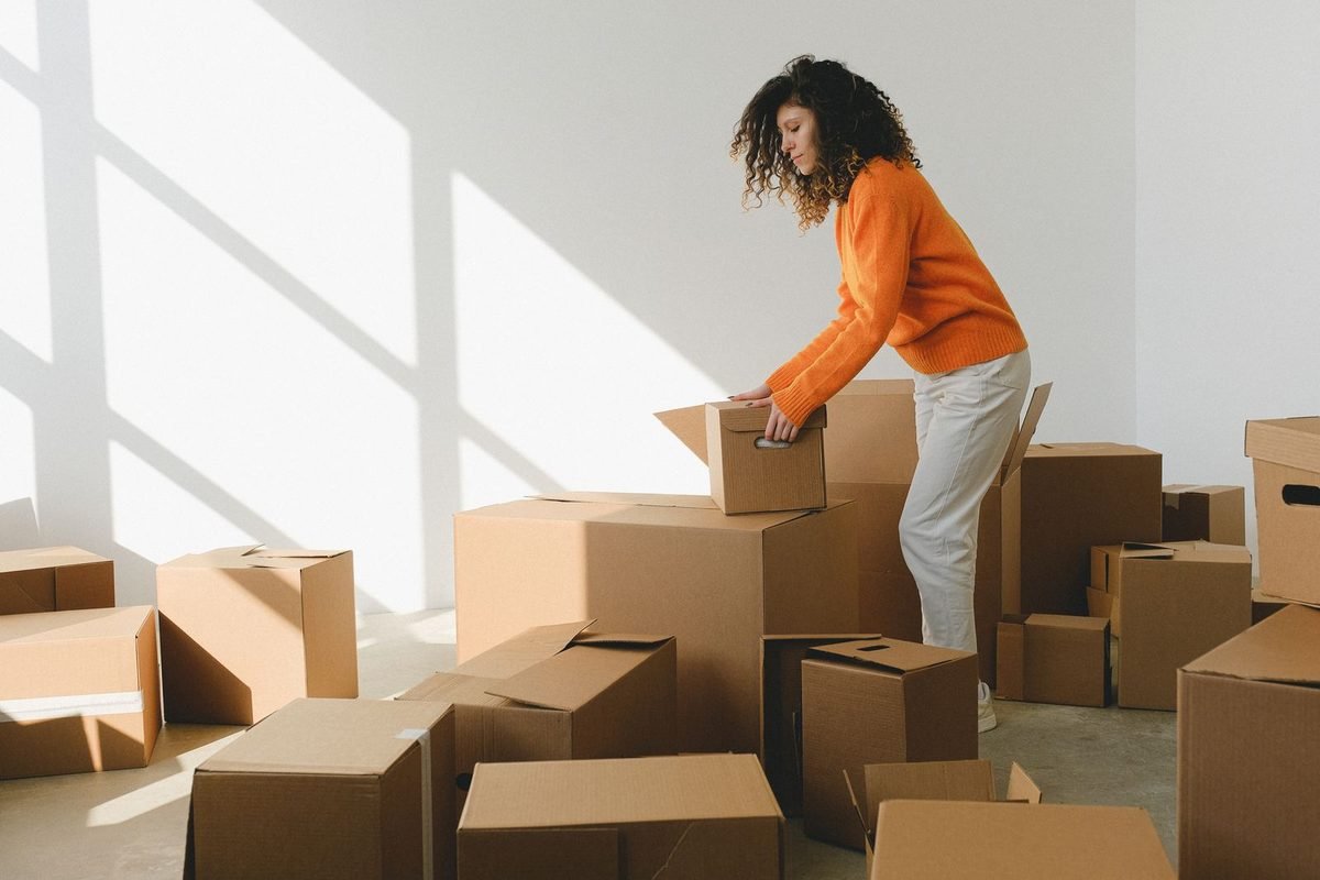 woman organizing a stack of cardboard boxes in a new apartment