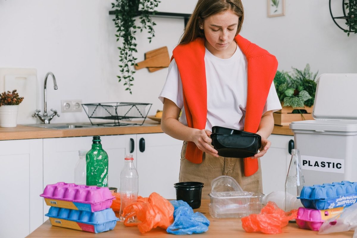 woman sorting items for recycling into bins in a kitchen