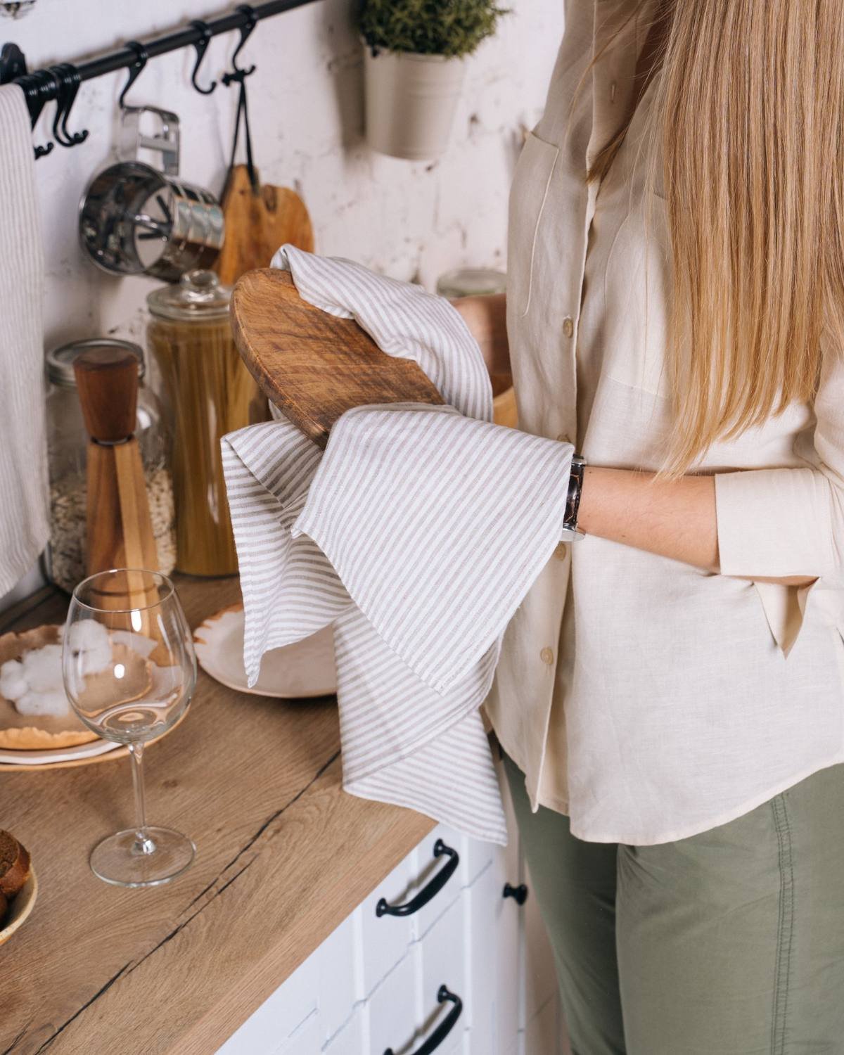 woman wiping a wooden kitchen counter with a linen towel