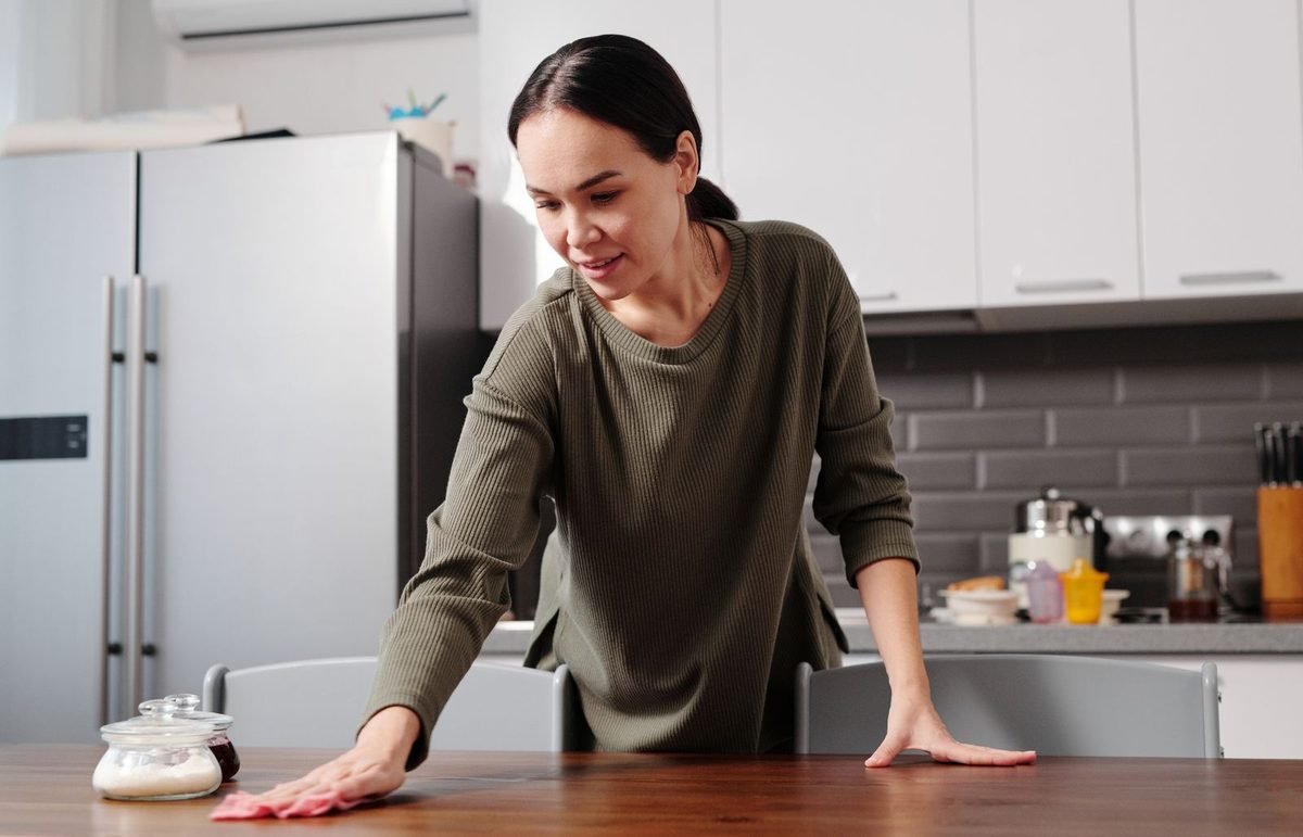 woman wiping down a kitchen table with a cloth