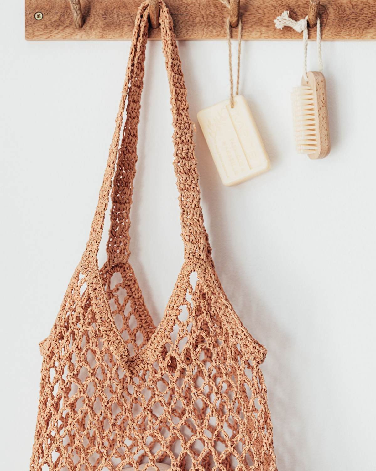 wooden peg hanger holding a mesh bag and bath brushes