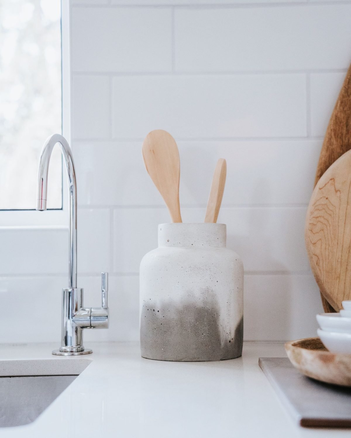 wooden spoon and tools in a ceramic jar on a white kitchen counter